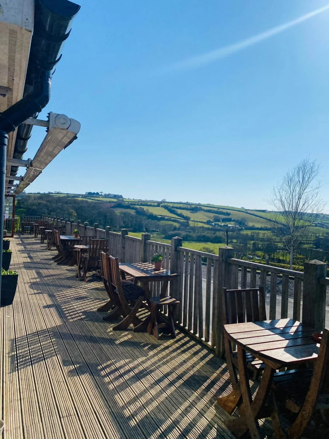 Tables on a wooden terrace overlooking green farmland