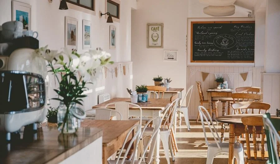 Sunlit café tables with flowers and pale chairs