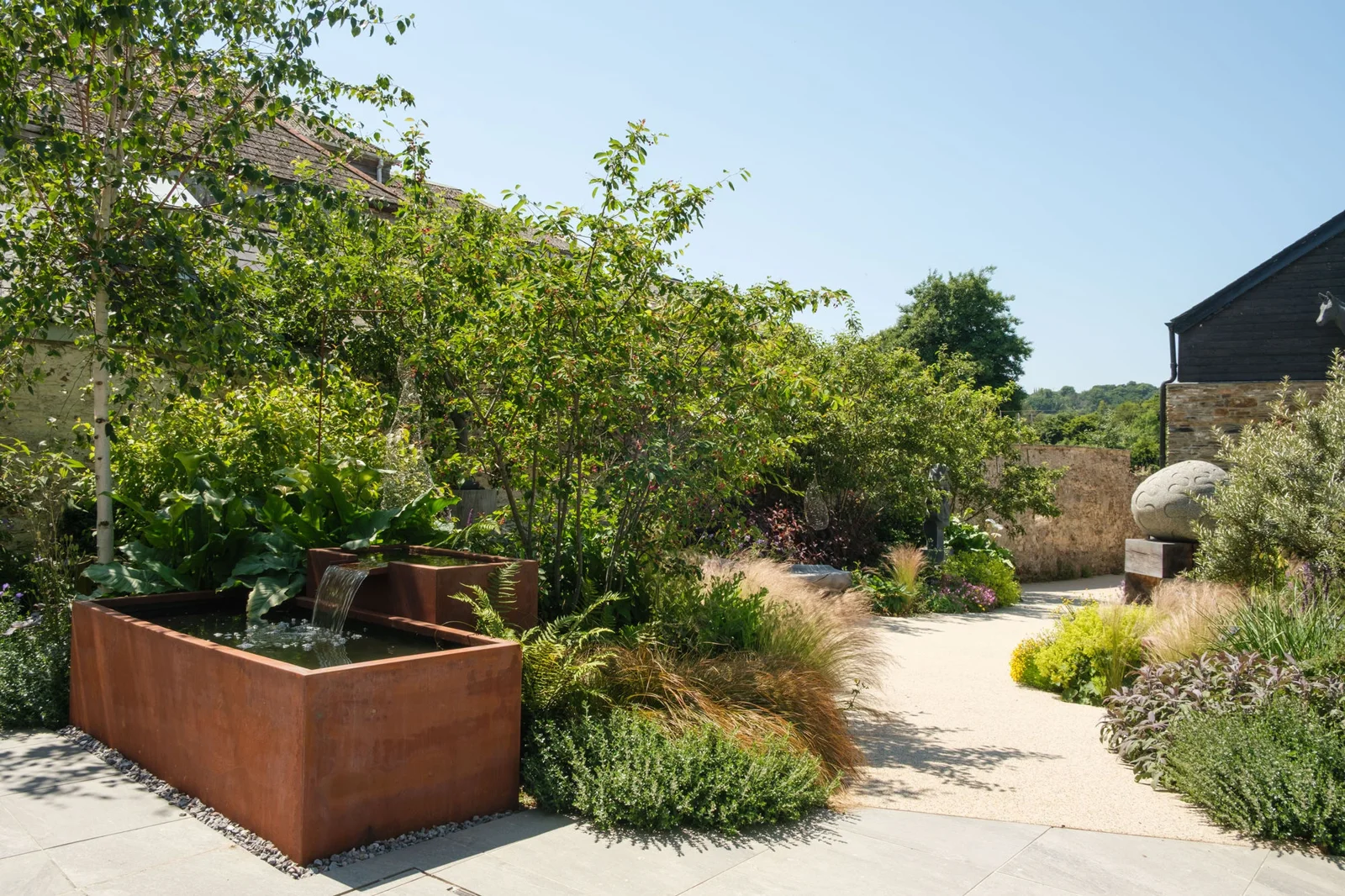 A planted path winding through Velarde’s walled sculpture garden