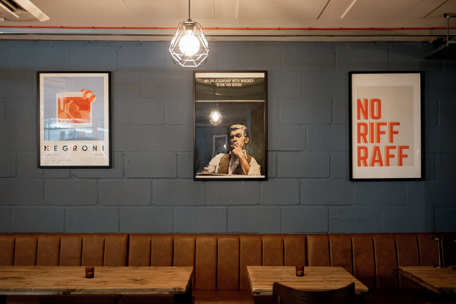 Dark panelled dining room with tan banquette seating and music artwork at Verse