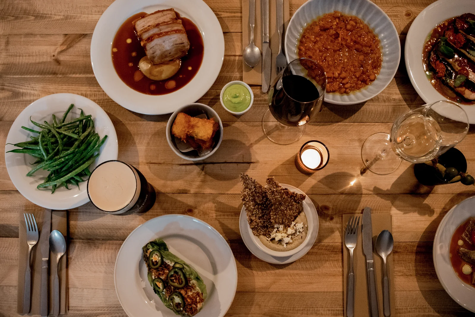 Several plated dishes and wine on a wooden table at Verse