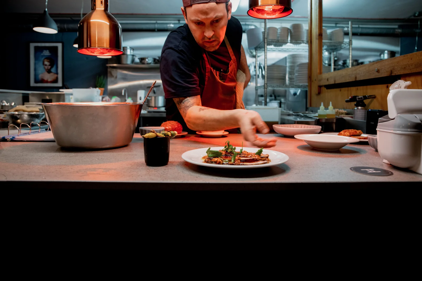 Chef plating dishes behind the kitchen counter at Verse
