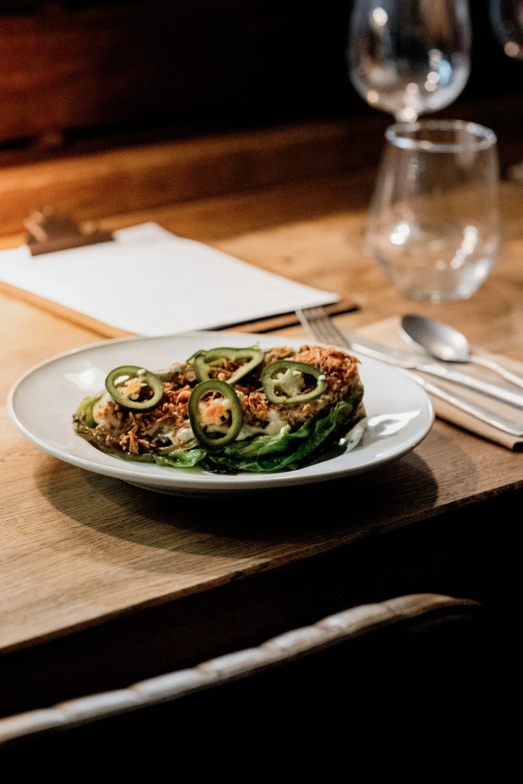 A plated green vegetable dish on a wooden restaurant table