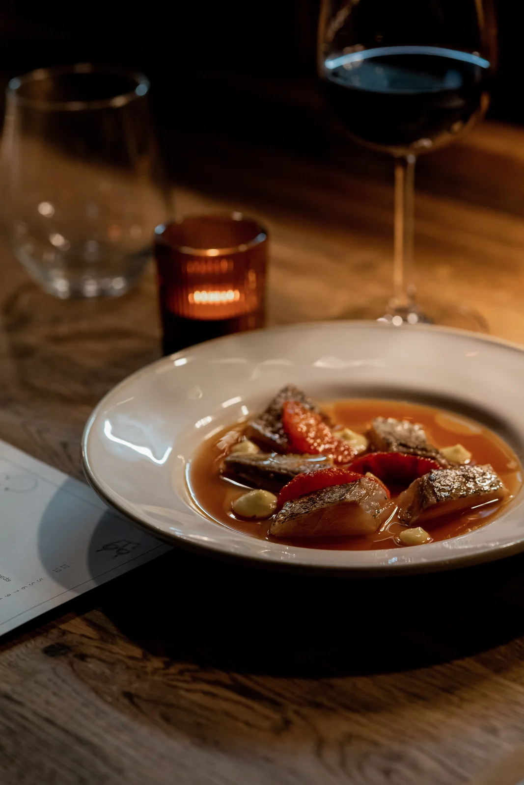 A plated dish beside a glass of red wine at Verse