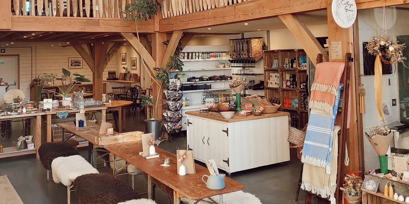 Timber-framed café interior with wooden tables, shelves and a counter