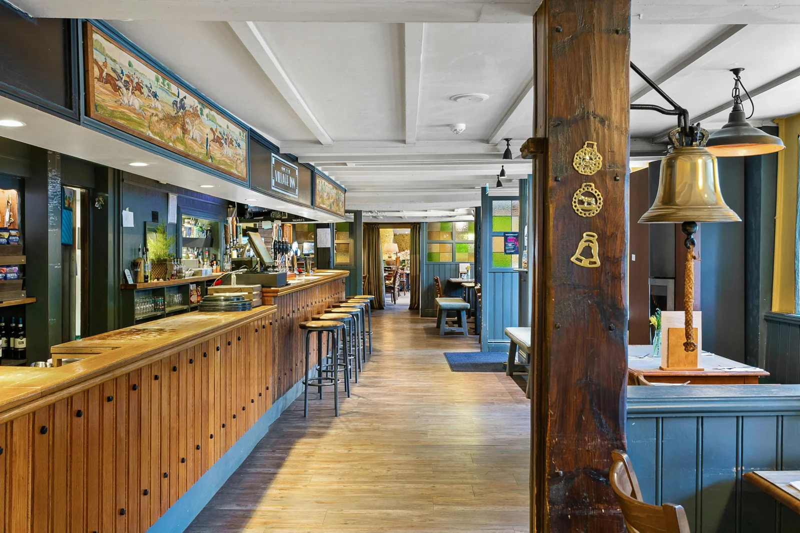 Long wooden pub bar with stools and exposed beams