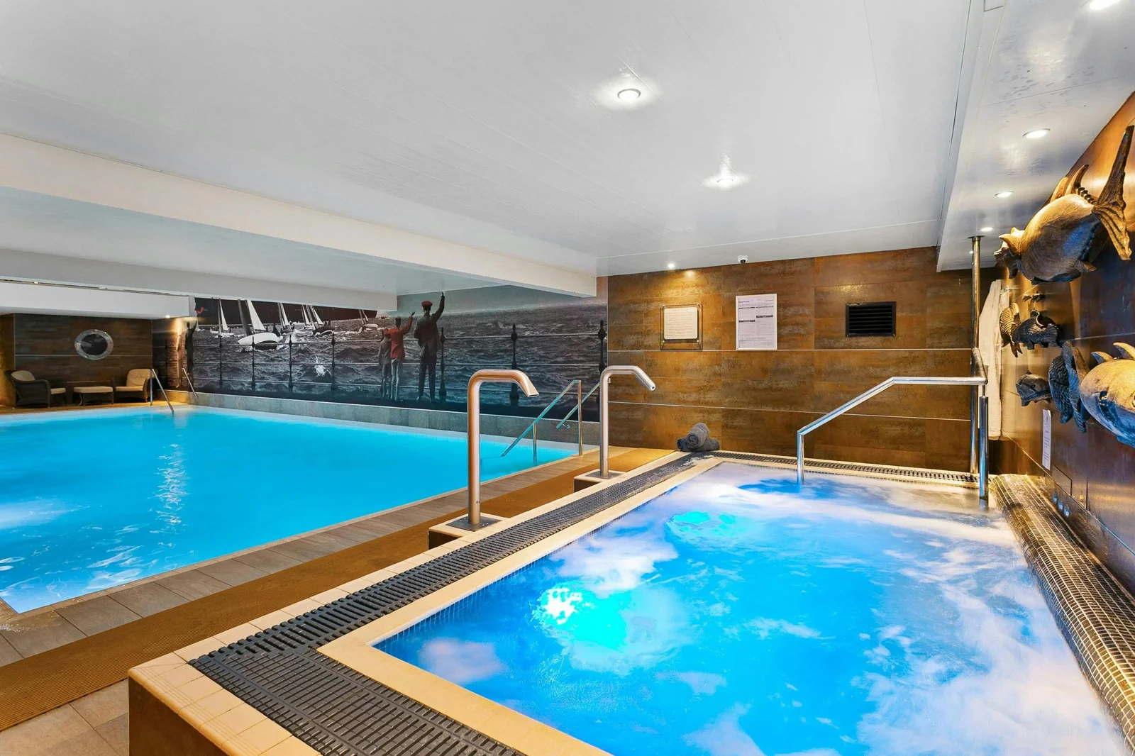 Indoor swimming pool and bubbling spa pool with loungers beyond