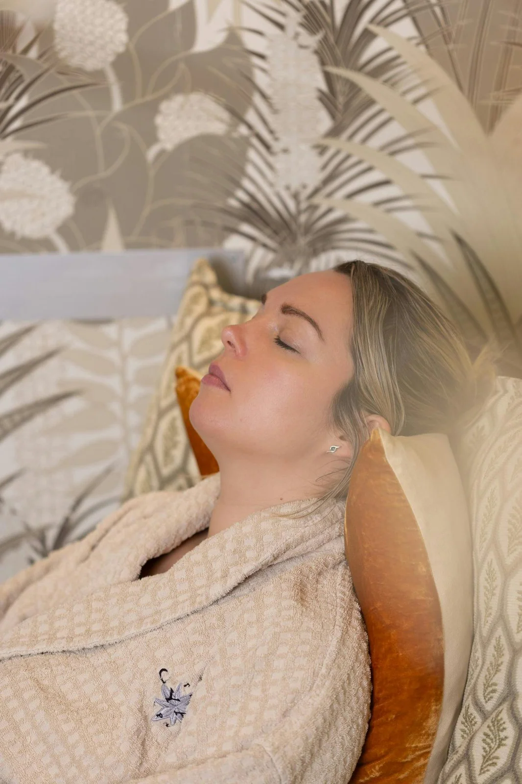 Guest wrapped in a robe relaxing beside botanical decor