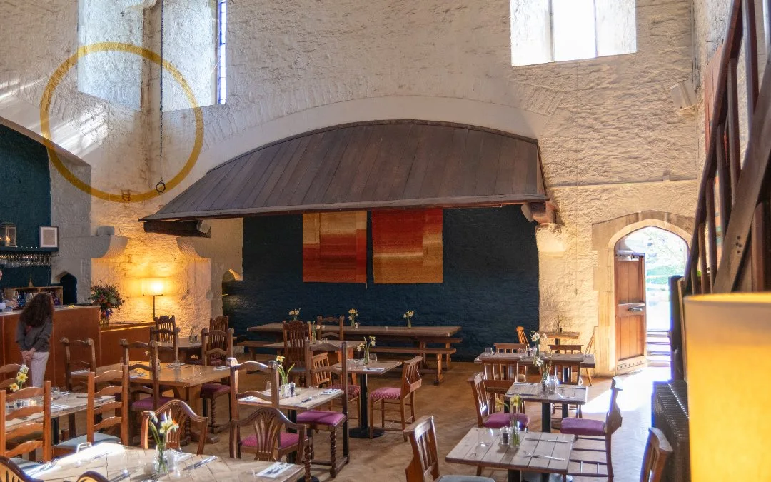 Historic dining hall with a large old fireplace at the White Hart in Dartington